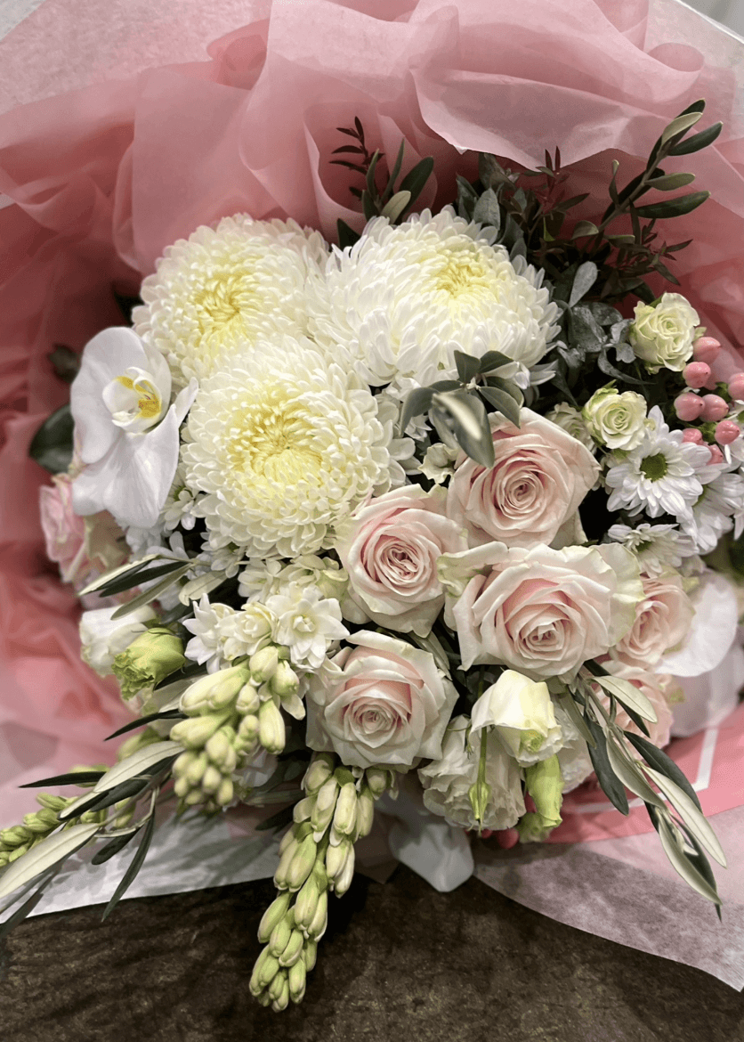 Pastel Promise bouquet featuring white and pink flowers wrapped in pink tissue by Berwick Flowers.