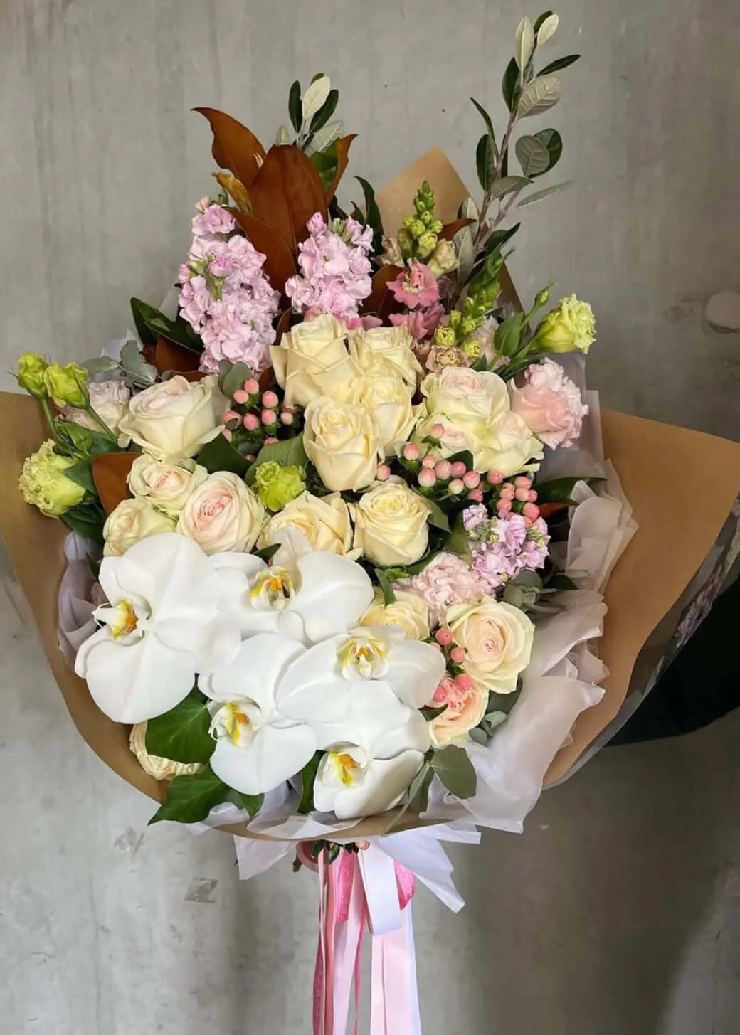 Florist Berwick Blushing Beauty bouquet featuring roses, orchids, and seasonal foliage in elegant wrapping.