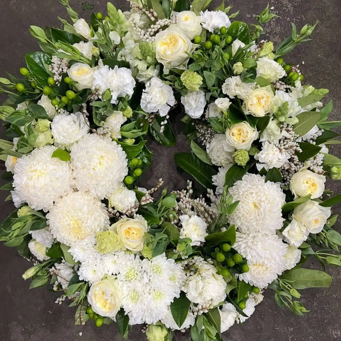 Pure white sympathy wreath by Berwick, featuring white flowers and soft green accents for a serene tribute.