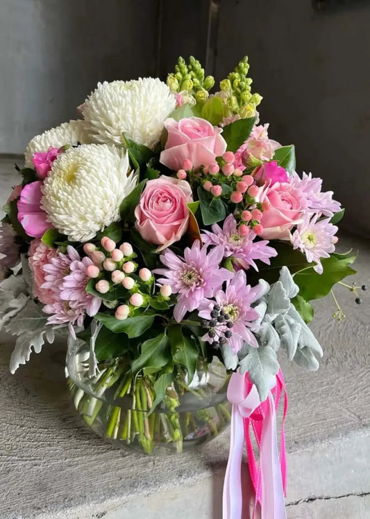 Bouquet of flowers with pink and white ribbons on a textured surface