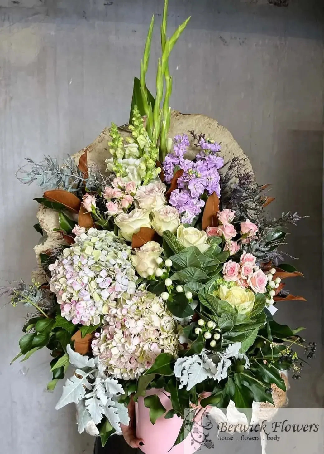 Bouquet of flowers in a pink vase against a gray background