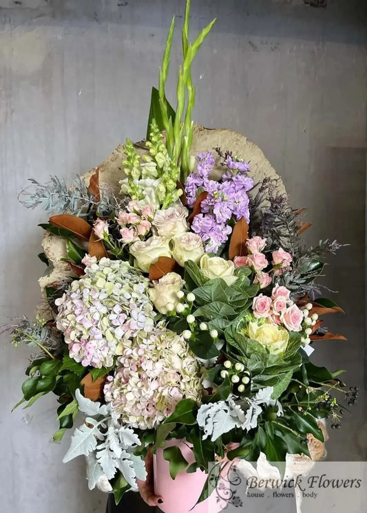 Bouquet of flowers in a pink vase against a gray background
