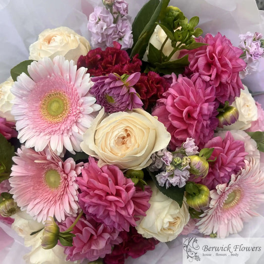 Bouquet of colorful flowers including pink, purple, and white blooms on a white background.