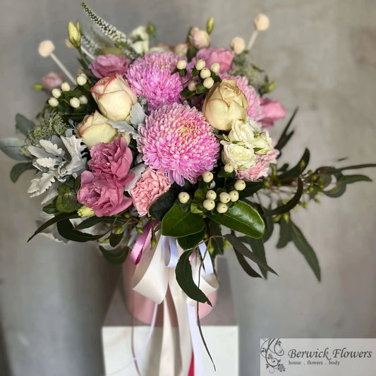 Bouquet of pink and white flowers with green leaves on a neutral background