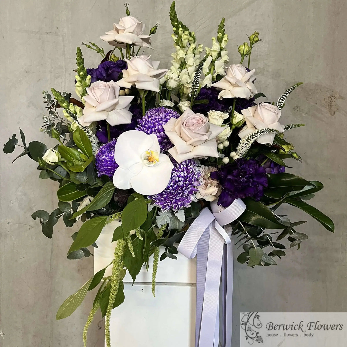 Bouquet of flowers with purple and white flowers in a vase against a gray background
