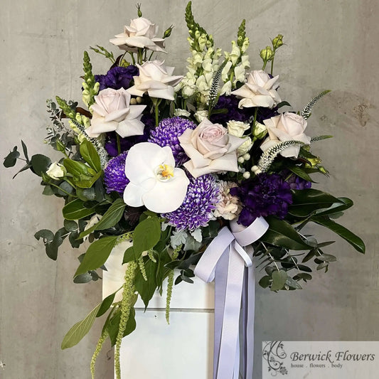 Bouquet of flowers with purple and white flowers in a vase against a gray background