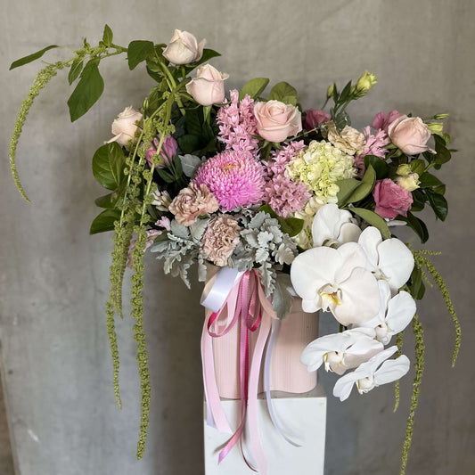 luxury flower vase filled with pink roses, orchids, and green foliage in a beautiful floral arrangement