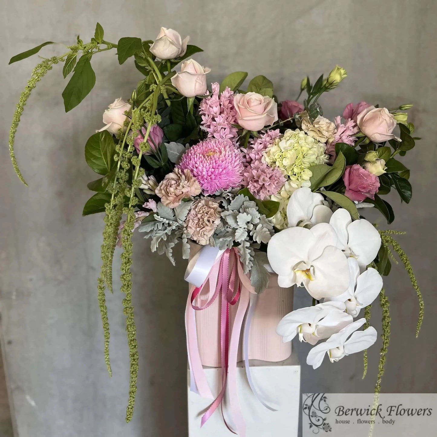 Bouquet of flowers with a pink ribbon in a white vase against a gray background