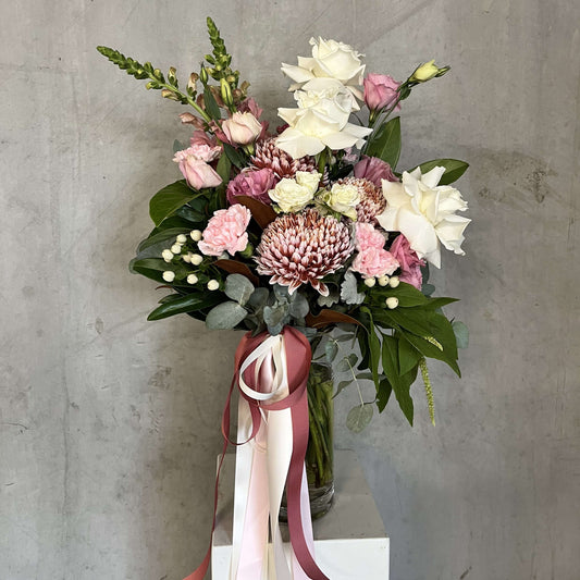 luxury vase arrangements featuring a stunning bouquet with roses, carnations, and a blend of foliage in a clear vase.