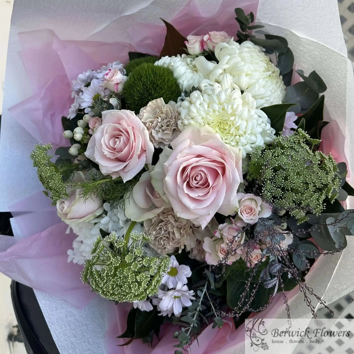 Bouquet of flowers wrapped in pink paper on a chair with a checkered pattern.