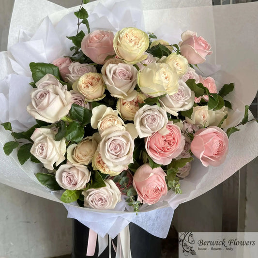 Bouquet of pink and white flowers wrapped in white paper on a plain background