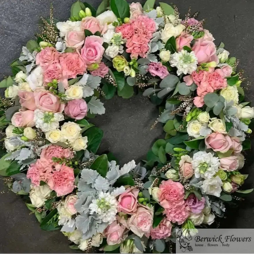 Floral wreath with pink, white, and green flowers on a dark background