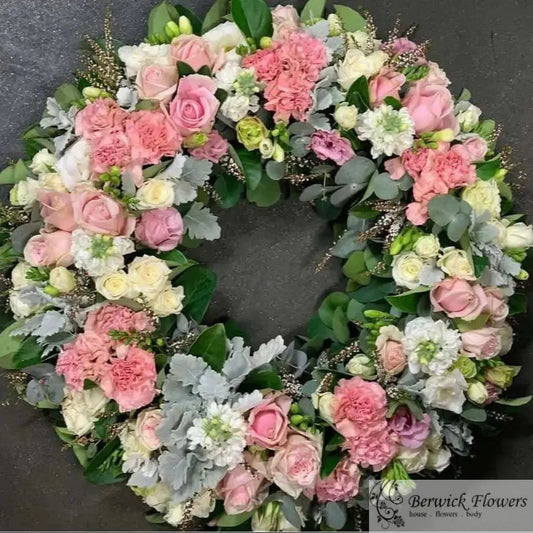 Floral wreath with pink, white, and green flowers on a dark background