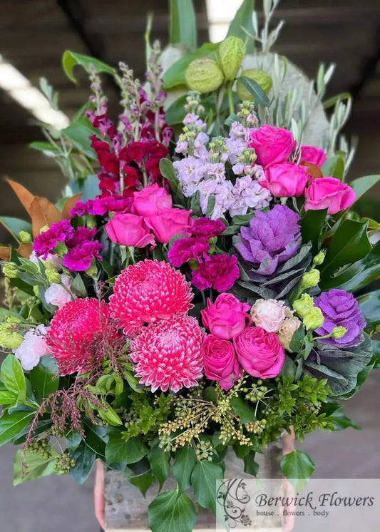 Bouquet of colorful flowers including pink, purple, and green in a clear vase.